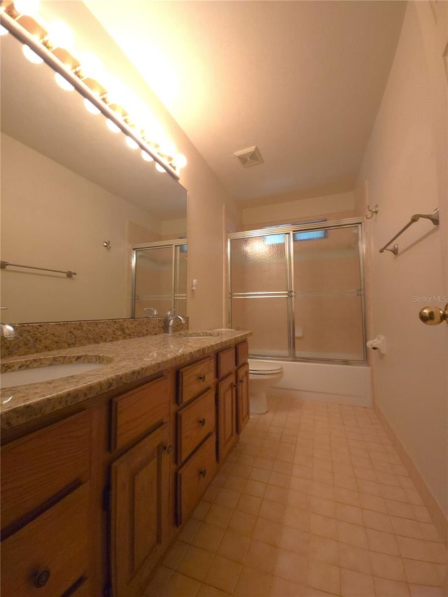7717 SW 22nd Ave, Gainesville, FL 32607 - full bathroom featuring toilet, double vanity, shower / bath combination with glass door, and tile patterned flooring