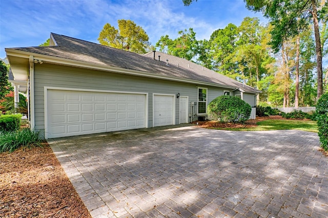4630 SW 95th Ter, Gainesville, FL 32608 - view of property exterior with decorative driveway, an attached garage, and a shingled roof