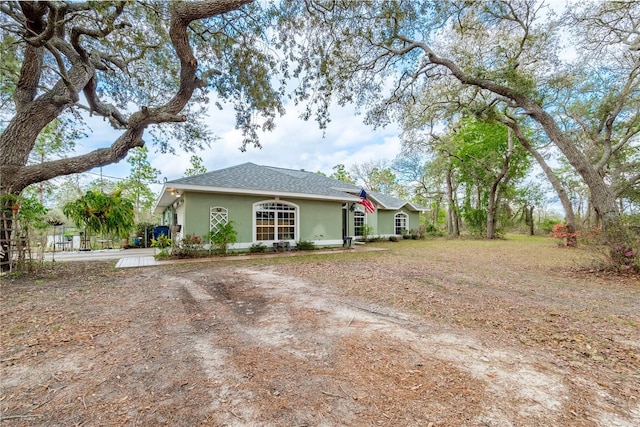 6550 SE 123rd Ter, Morriston, FL 32668 - exterior space with a shingled roof, stucco siding, and dirt driveway