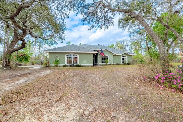 6550 SE 123rd Ter, Morriston, FL 32668 - view of front of house with stucco siding, a shingled roof, and dirt driveway