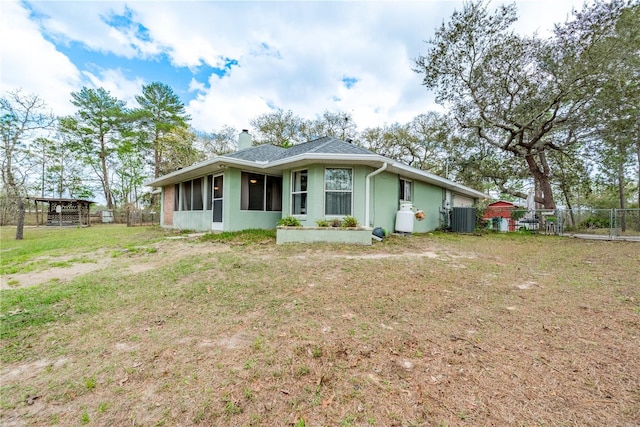 6550 SE 123rd Ter, Morriston, FL 32668 - view of front of home featuring a front yard, central air condition unit, a chimney, stucco siding, and fence