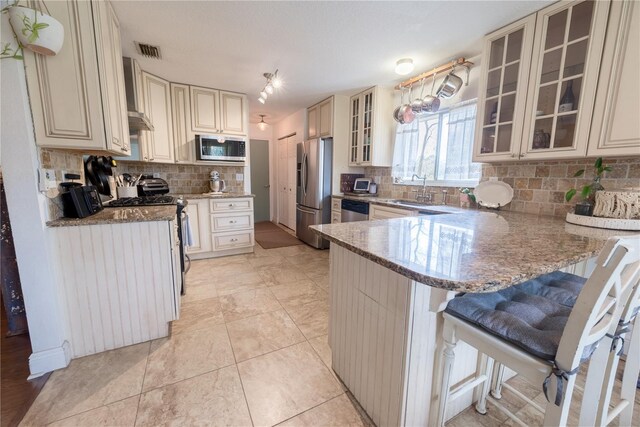 6550 SE 123rd Ter, Morriston, FL 32668 - kitchen featuring stone counters, a peninsula, stainless steel appliances, visible vents, and cream cabinetry