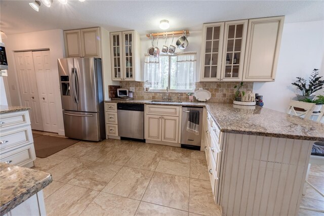 6550 SE 123rd Ter, Morriston, FL 32668 - kitchen featuring decorative backsplash, cream cabinets, a sink, a peninsula, and appliances with stainless steel finishes
