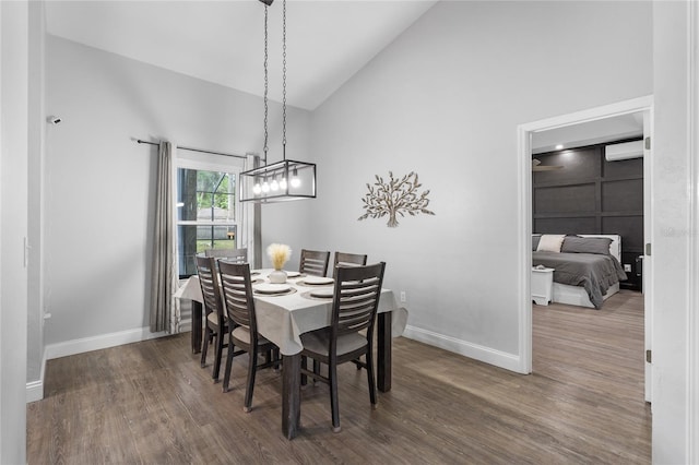 dining area with baseboards, high vaulted ceiling, and wood finished floors