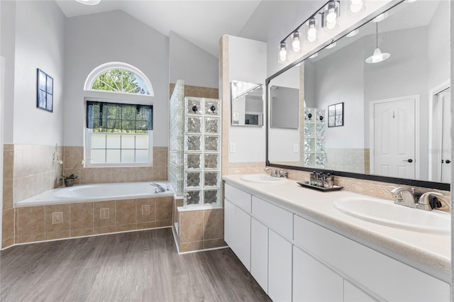 full bathroom featuring wood finished floors, a sink, a garden tub, and lofted ceiling