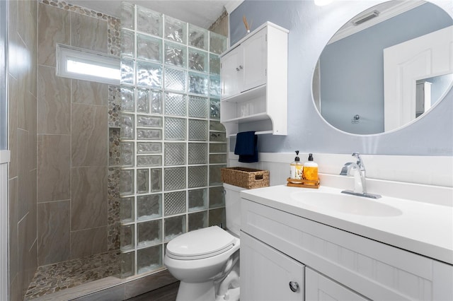 bathroom featuring toilet, visible vents, walk in shower, and vanity