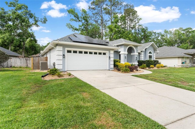 ranch-style house featuring driveway, an attached garage, central AC, fence, and roof mounted solar panels
