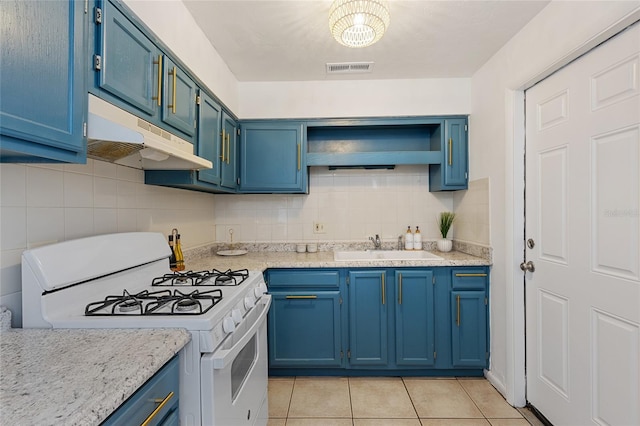 kitchen with a sink, gas range gas stove, blue cabinets, under cabinet range hood, and light tile patterned floors