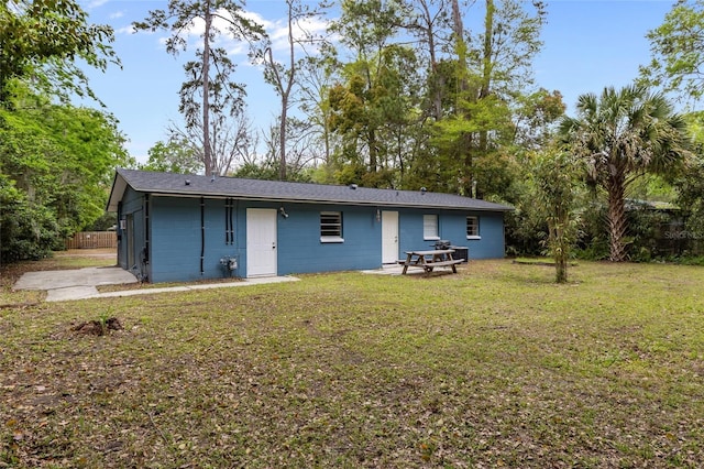 rear view of house featuring fence and a yard