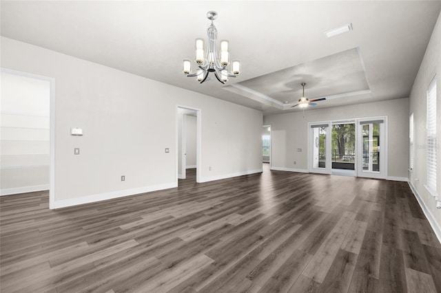 unfurnished living room featuring baseboards, dark wood-style flooring, a tray ceiling, and ceiling fan with notable chandelier