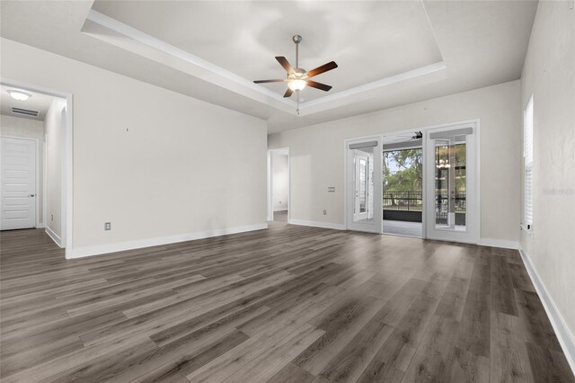unfurnished room featuring a ceiling fan, dark wood-style floors, a tray ceiling, and baseboards