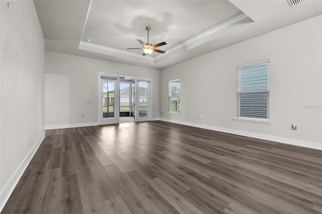 spare room featuring dark wood-type flooring, a tray ceiling, baseboards, and ceiling fan