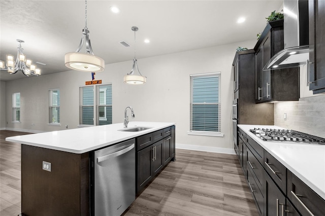 kitchen with light countertops, visible vents, wall chimney exhaust hood, stainless steel appliances, and a sink