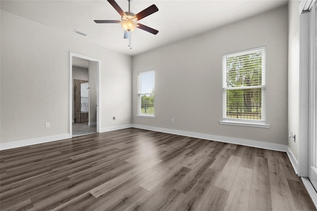 unfurnished room with dark wood-style flooring, visible vents, and a wealth of natural light