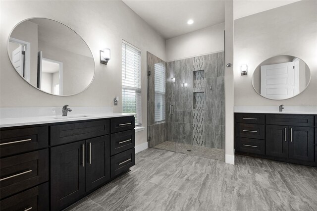 bathroom featuring a shower stall, a sink, and two vanities