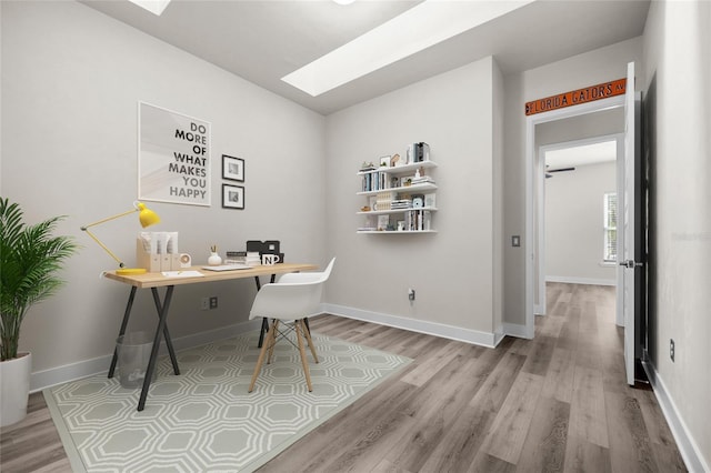 office space featuring a skylight, baseboards, and wood finished floors
