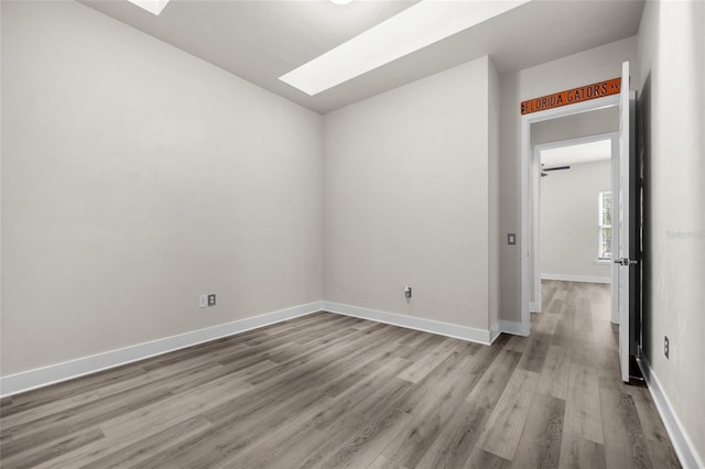 empty room with baseboards, wood finished floors, and a skylight