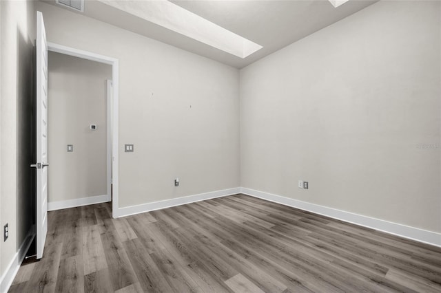 spare room featuring baseboards, visible vents, wood finished floors, and a skylight