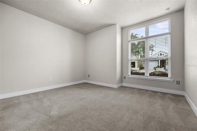 carpeted empty room featuring baseboards