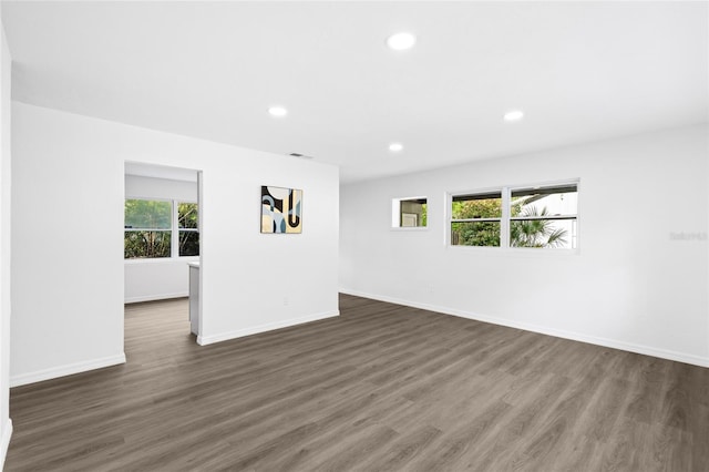 spare room with dark wood-style floors, visible vents, baseboards, and recessed lighting