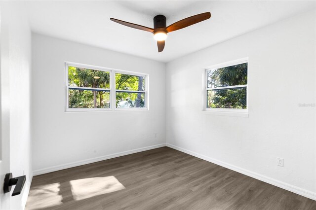 spare room featuring baseboards, a wealth of natural light, wood finished floors, and ceiling fan