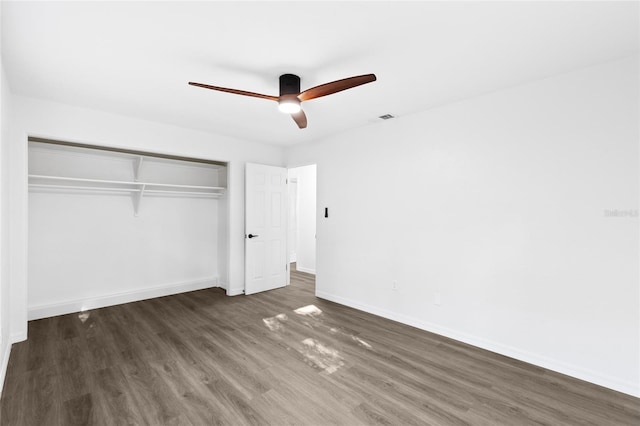 unfurnished bedroom featuring baseboards, visible vents, a ceiling fan, a closet, and wood finished floors
