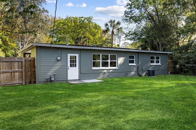 back of house with cooling unit, a yard, fence, and concrete block siding