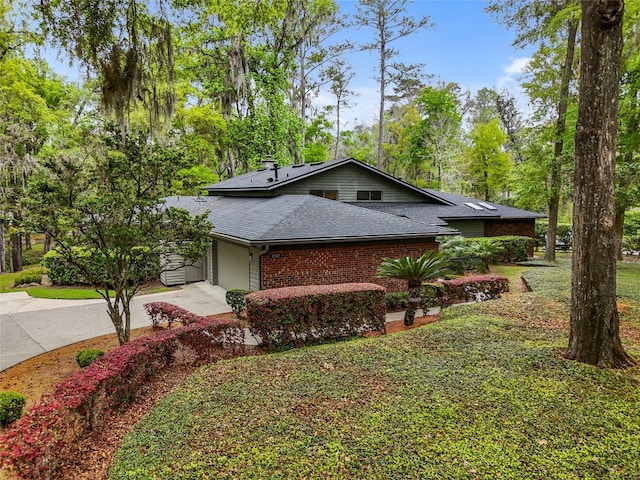 11112 Palmetto Blvd, Alachua, FL 32615 - view of home's exterior featuring concrete driveway, roof with shingles, brick siding, a garage, and a lawn