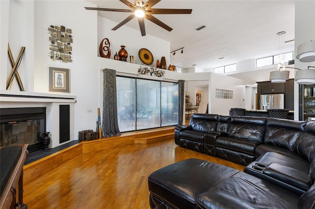 11112 Palmetto Blvd, Alachua, FL 32615 - living area featuring a ceiling fan, a high ceiling, wood finished floors, a glass covered fireplace, and visible vents