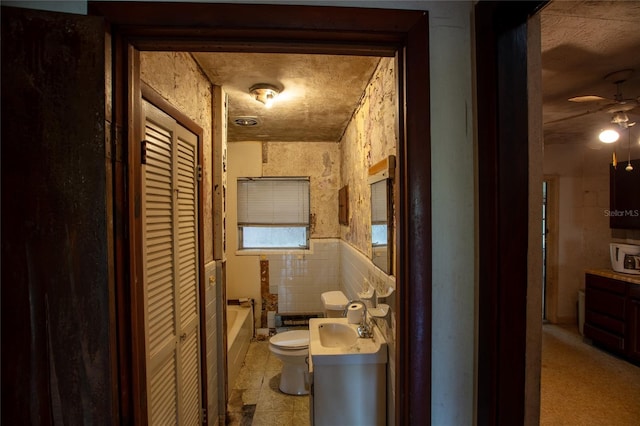 198 SE 59th St, Keystone Heights, FL 32656 - full bathroom with tile walls, a tub, toilet, a ceiling fan, and a closet