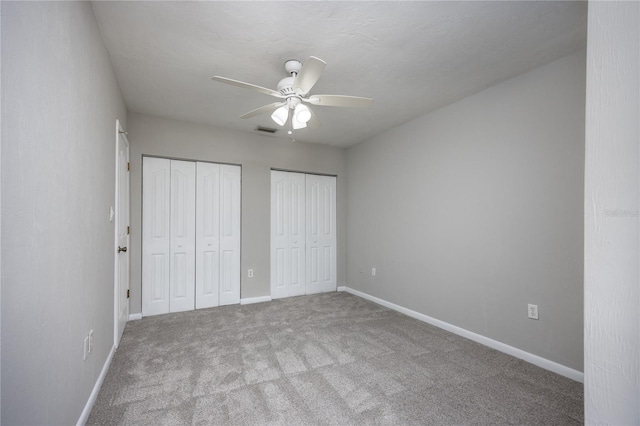 501 SW 75th St Unit E3, Gainesville, FL 32607 - unfurnished bedroom featuring two closets, carpet floors, baseboards, and a ceiling fan