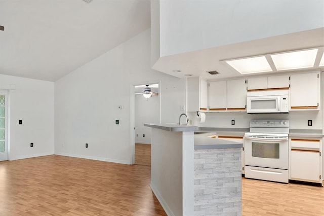 kitchen with light countertops, a peninsula, light wood-style floors, and white appliances