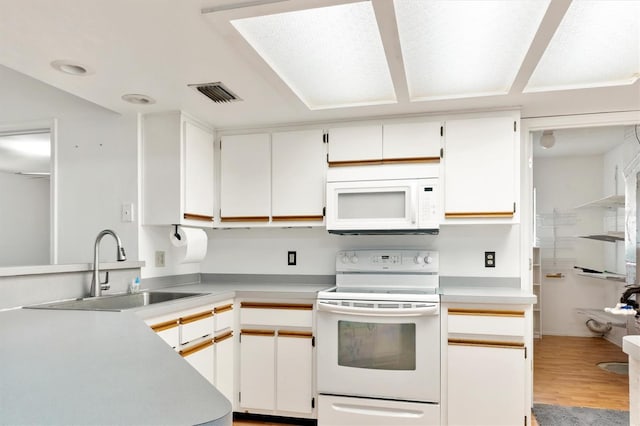 kitchen featuring light countertops, white appliances, a sink, visible vents, and wood finished floors