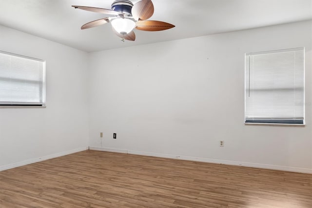 spare room featuring baseboards, light wood-type flooring, and ceiling fan