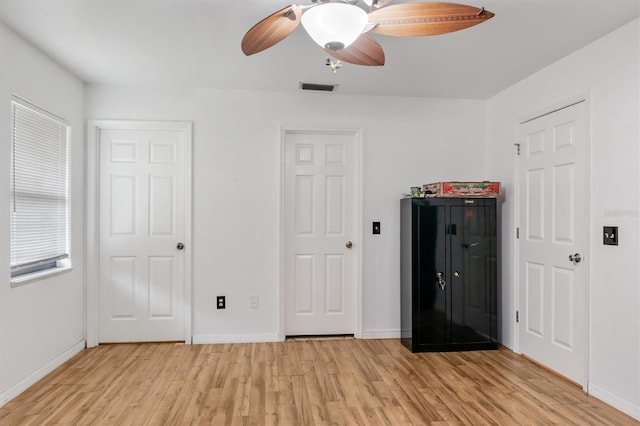 unfurnished bedroom featuring baseboards, ceiling fan, visible vents, and light wood-style floors