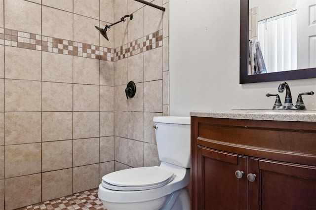 full bath featuring a tile shower, toilet, and vanity