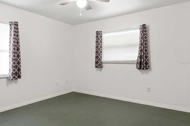 spare room featuring concrete floors, a wealth of natural light, baseboards, and ceiling fan