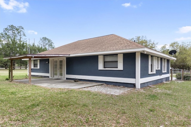 rear view of house with a patio, a shingled roof, french doors, and a yard