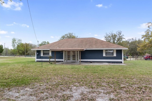 rear view of house with french doors, roof with shingles, and a yard