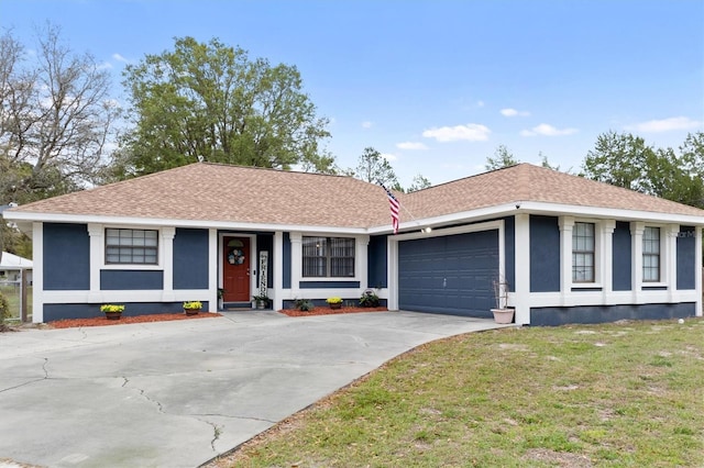 ranch-style home with a garage, concrete driveway, a front yard, roof with shingles, and stucco siding