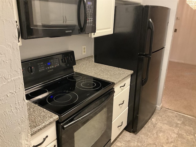 kitchen featuring light stone counters, white cabinetry, black appliances, and light tile patterned floors