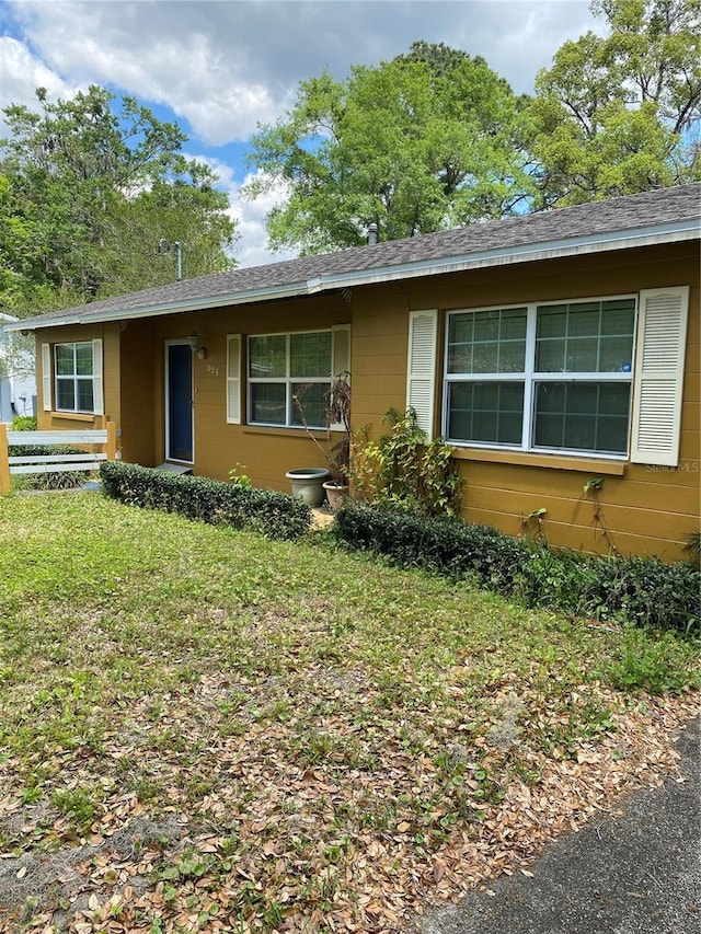 ranch-style home with a front lawn and roof with shingles