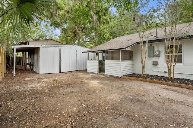 4120 NW 10th St, Gainesville, FL 32609 - view of side of property featuring roof with shingles, an outdoor structure, concrete block siding, and a sunroom