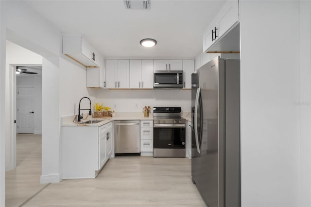 4120 NW 10th St, Gainesville, FL 32609 - kitchen with stainless steel appliances, light wood-style flooring, white cabinetry, light countertops, and a ceiling fan