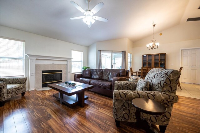 living room with visible vents, a tiled fireplace, wood finished floors, ceiling fan with notable chandelier, and lofted ceiling