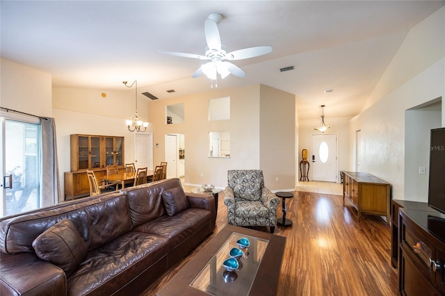 living room featuring high vaulted ceiling, ceiling fan with notable chandelier, wood finished floors, and visible vents