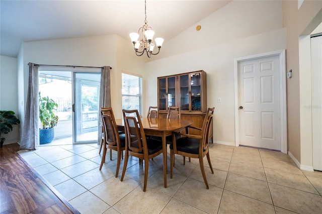 dining space with baseboards, light tile patterned floors, a notable chandelier, and vaulted ceiling