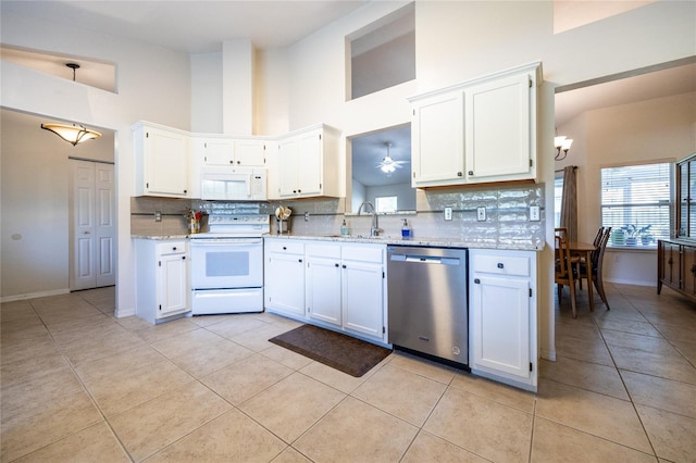 kitchen featuring tasteful backsplash, white appliances, light tile patterned flooring, and a high ceiling
