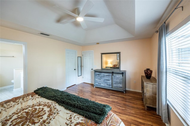 bedroom featuring baseboards, visible vents, wood finished floors, and a raised ceiling
