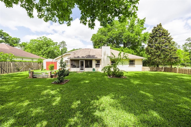 rear view of property featuring a storage unit, a fenced backyard, a lawn, and a chimney